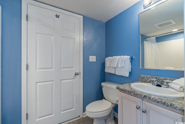 bathroom featuring vanity, toilet, a textured ceiling, and tile patterned flooring