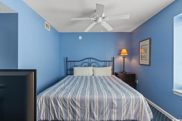 carpeted bedroom featuring visible vents, a ceiling fan, and a textured ceiling