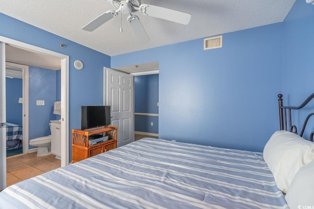 bedroom featuring visible vents, ceiling fan, a textured ceiling, tile patterned floors, and ensuite bath