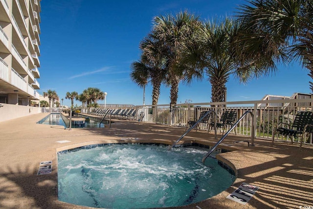 pool with a hot tub, fence, and a patio area