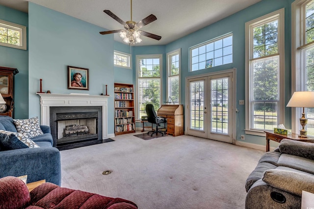 living room with a towering ceiling, plenty of natural light, and light colored carpet