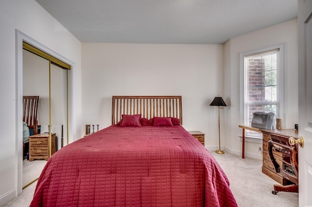 bedroom featuring light carpet, a textured ceiling, and a closet