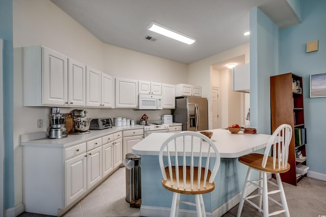 kitchen featuring a breakfast bar, white cabinetry, white appliances, and light tile patterned flooring