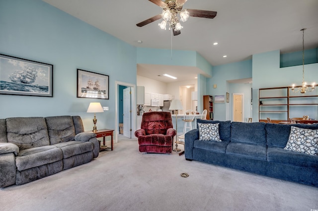 carpeted living room featuring a high ceiling and ceiling fan with notable chandelier