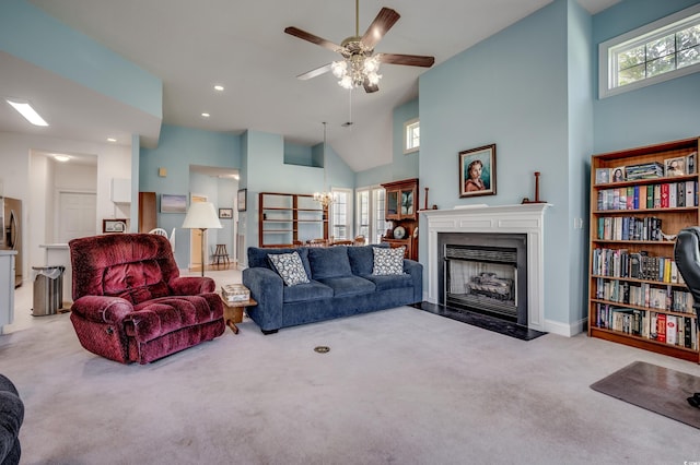 carpeted living room featuring a towering ceiling and ceiling fan with notable chandelier