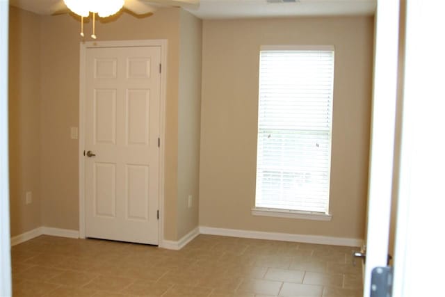 unfurnished room with ceiling fan and light tile patterned floors