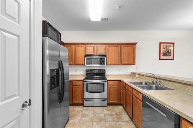 kitchen with light tile patterned floors, stainless steel appliances, a textured ceiling, and sink