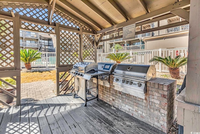 wooden terrace featuring exterior kitchen and a grill