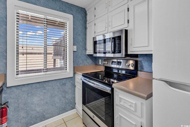 kitchen with stainless steel appliances, light tile patterned flooring, and white cabinets