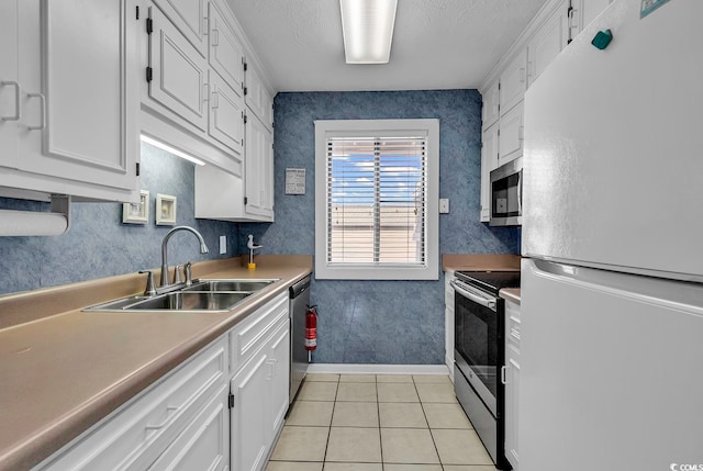 kitchen featuring appliances with stainless steel finishes, white cabinets, sink, and light tile patterned floors