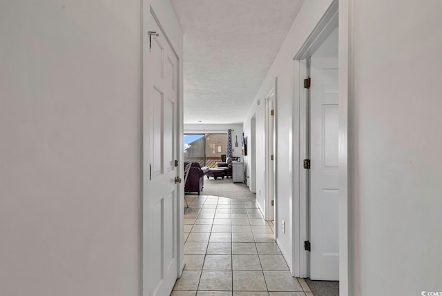 hallway featuring a textured ceiling and light tile patterned floors