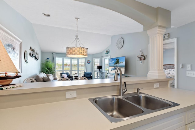 kitchen featuring decorative columns, vaulted ceiling, sink, and decorative light fixtures