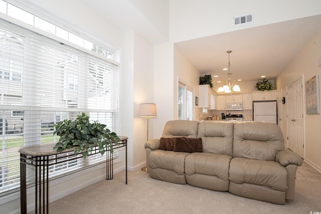 living room featuring light colored carpet and a notable chandelier