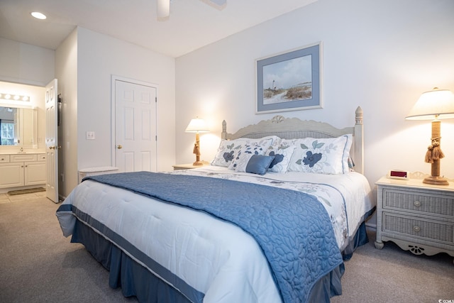 bedroom featuring ceiling fan, light colored carpet, and ensuite bath