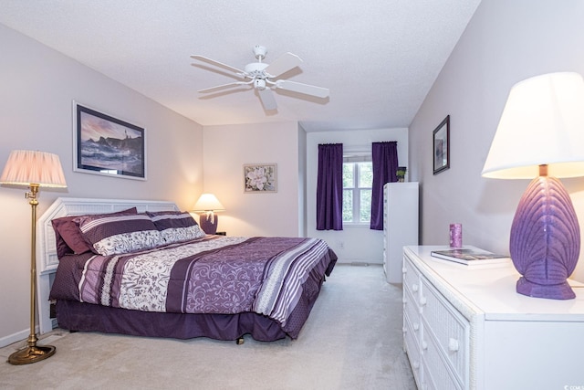 bedroom featuring a textured ceiling, light colored carpet, and ceiling fan