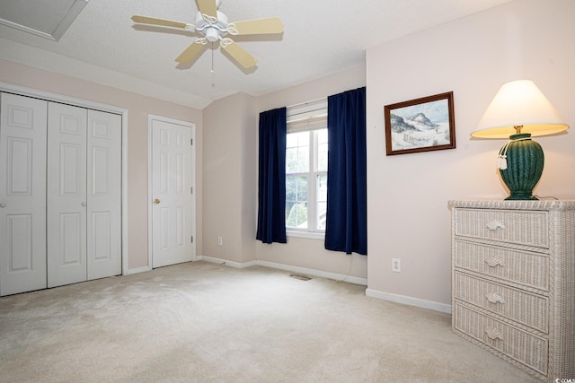 unfurnished bedroom with light carpet, a textured ceiling, and ceiling fan