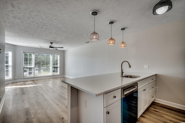 kitchen with dishwasher, sink, light hardwood / wood-style floors, decorative light fixtures, and white cabinets