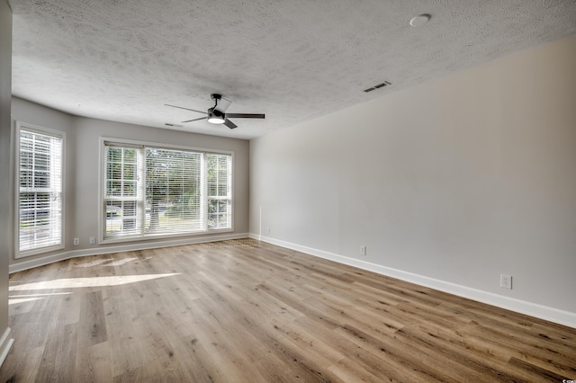 empty room with ceiling fan, a textured ceiling, and light wood-type flooring