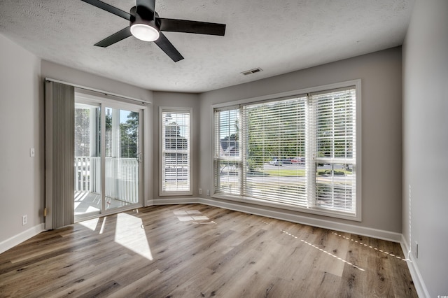 spare room with a textured ceiling, light wood-type flooring, and ceiling fan