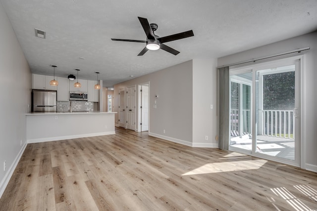 unfurnished living room featuring light hardwood / wood-style floors, a textured ceiling, and ceiling fan