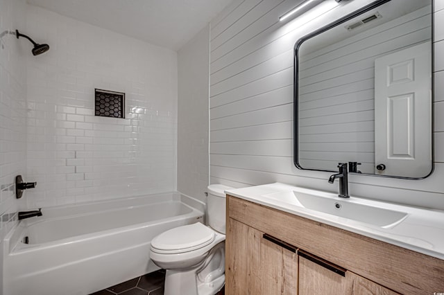 full bathroom with vanity, tiled shower / bath combo, toilet, and wood walls