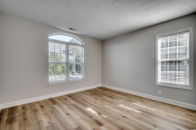 unfurnished room with a textured ceiling and light wood-type flooring