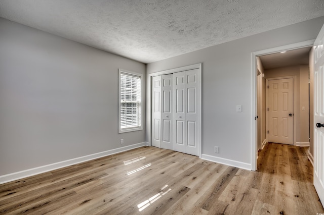 unfurnished bedroom featuring a closet, a textured ceiling, and light hardwood / wood-style floors