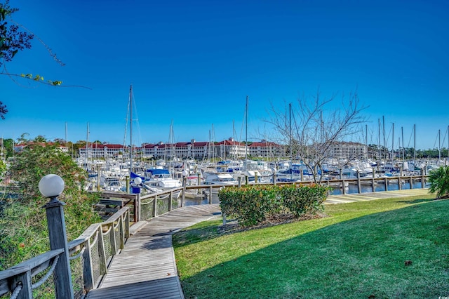 view of dock with a water view and a lawn