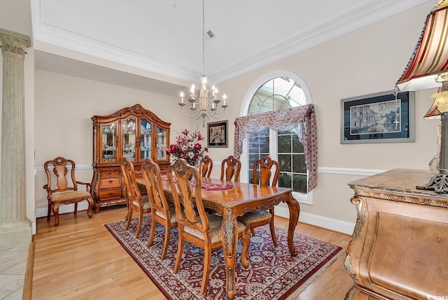 dining space featuring ornamental molding, light wood-type flooring, decorative columns, and a notable chandelier