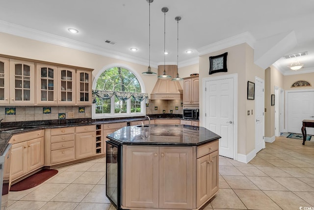 kitchen with pendant lighting, light brown cabinetry, a kitchen island with sink, and light tile patterned floors