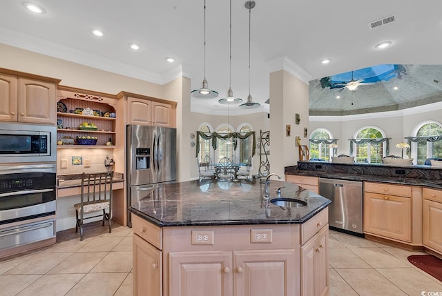 kitchen with sink, appliances with stainless steel finishes, a center island with sink, light brown cabinetry, and decorative light fixtures