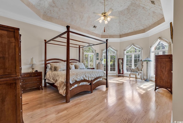 bedroom with crown molding, ceiling fan, light wood-type flooring, and a tray ceiling