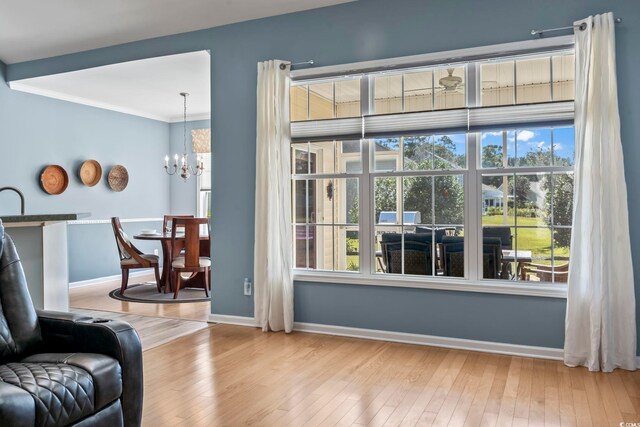 living room with a towering ceiling, light hardwood / wood-style floors, and ceiling fan with notable chandelier