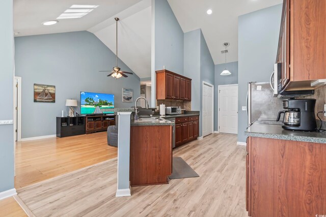 kitchen with stainless steel appliances, lofted ceiling, sink, backsplash, and light hardwood / wood-style flooring