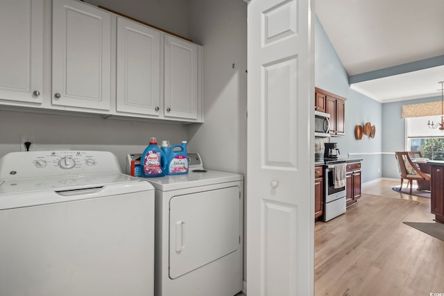 laundry room featuring light wood-type flooring, cabinets, washing machine and clothes dryer, and a notable chandelier