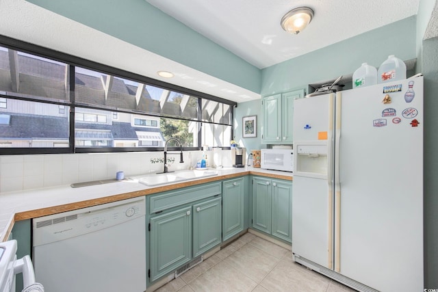 kitchen featuring sink, backsplash, a textured ceiling, white appliances, and light tile patterned floors