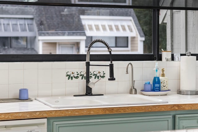 details with decorative backsplash, green cabinetry, dishwasher, and sink