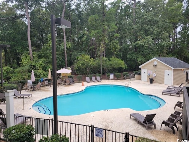 view of pool with an outbuilding and a patio