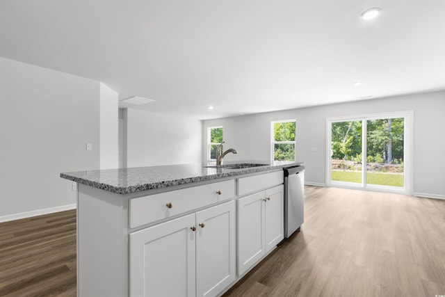 kitchen featuring white cabinetry, hardwood / wood-style flooring, dishwasher, and a kitchen island with sink