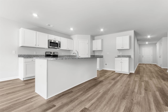 kitchen featuring appliances with stainless steel finishes, white cabinets, and a center island with sink