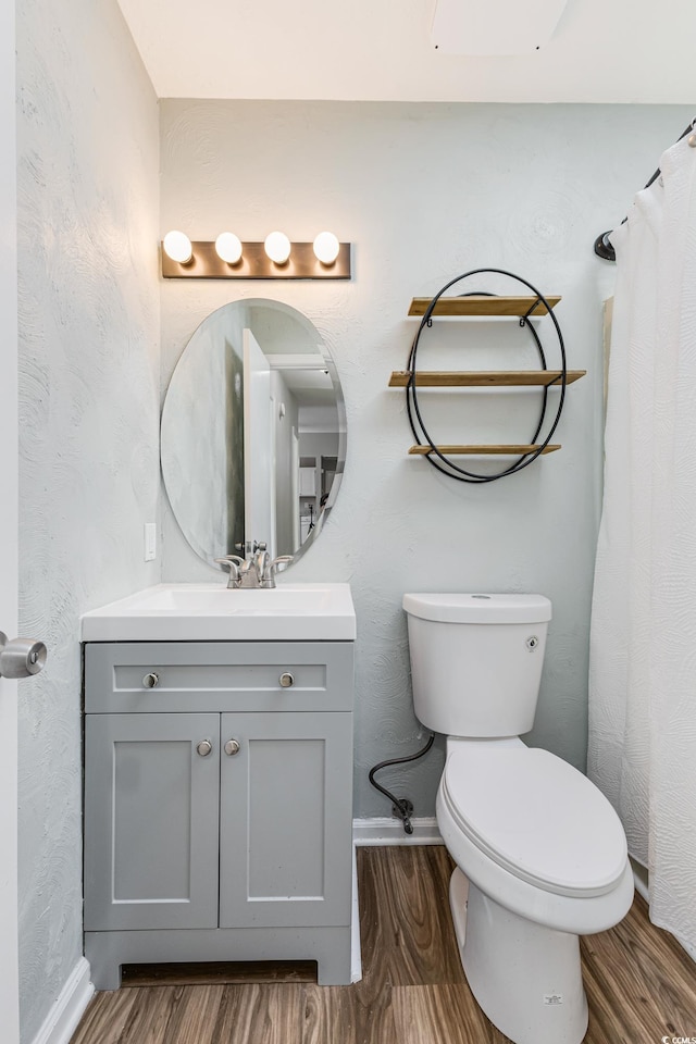 bathroom featuring toilet, curtained shower, hardwood / wood-style flooring, and vanity