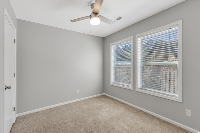 spare room featuring ceiling fan, a healthy amount of sunlight, and light colored carpet