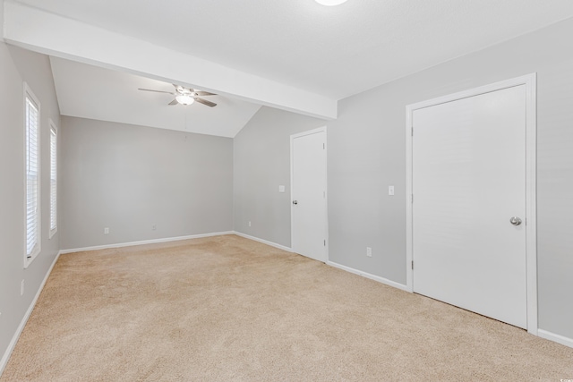 interior space with ceiling fan, vaulted ceiling with beams, and light colored carpet