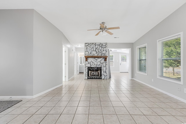 unfurnished living room featuring ceiling fan, light tile patterned flooring, a fireplace, and vaulted ceiling