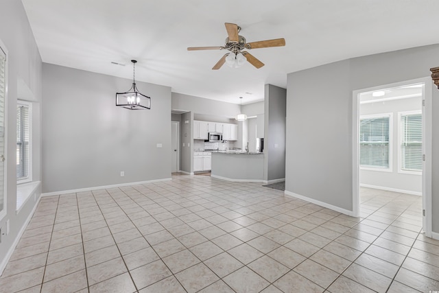 unfurnished living room featuring light tile patterned floors and ceiling fan with notable chandelier