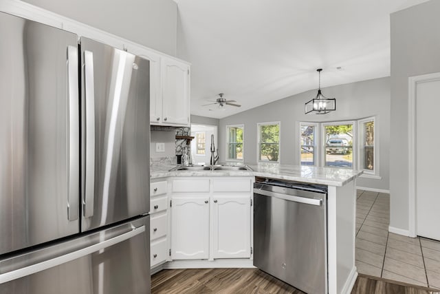 kitchen with kitchen peninsula, stainless steel appliances, sink, vaulted ceiling, and white cabinets