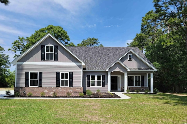craftsman house featuring brick siding, a front yard, and a shingled roof