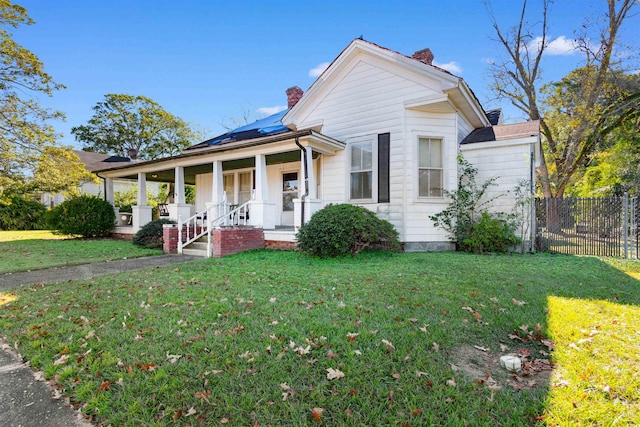 view of front of house with solar panels, a porch, and a front yard