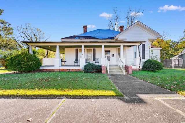 view of front of home with a front yard, solar panels, and a porch