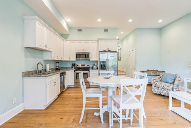 kitchen with sink, white cabinetry, light hardwood / wood-style flooring, and stainless steel appliances